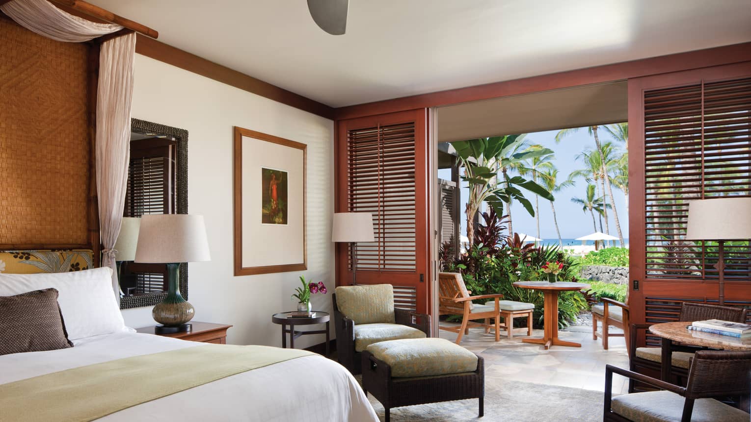 Ocean-View Room bed, wicker armchair and ottoman, wood shutters by open wall to patio