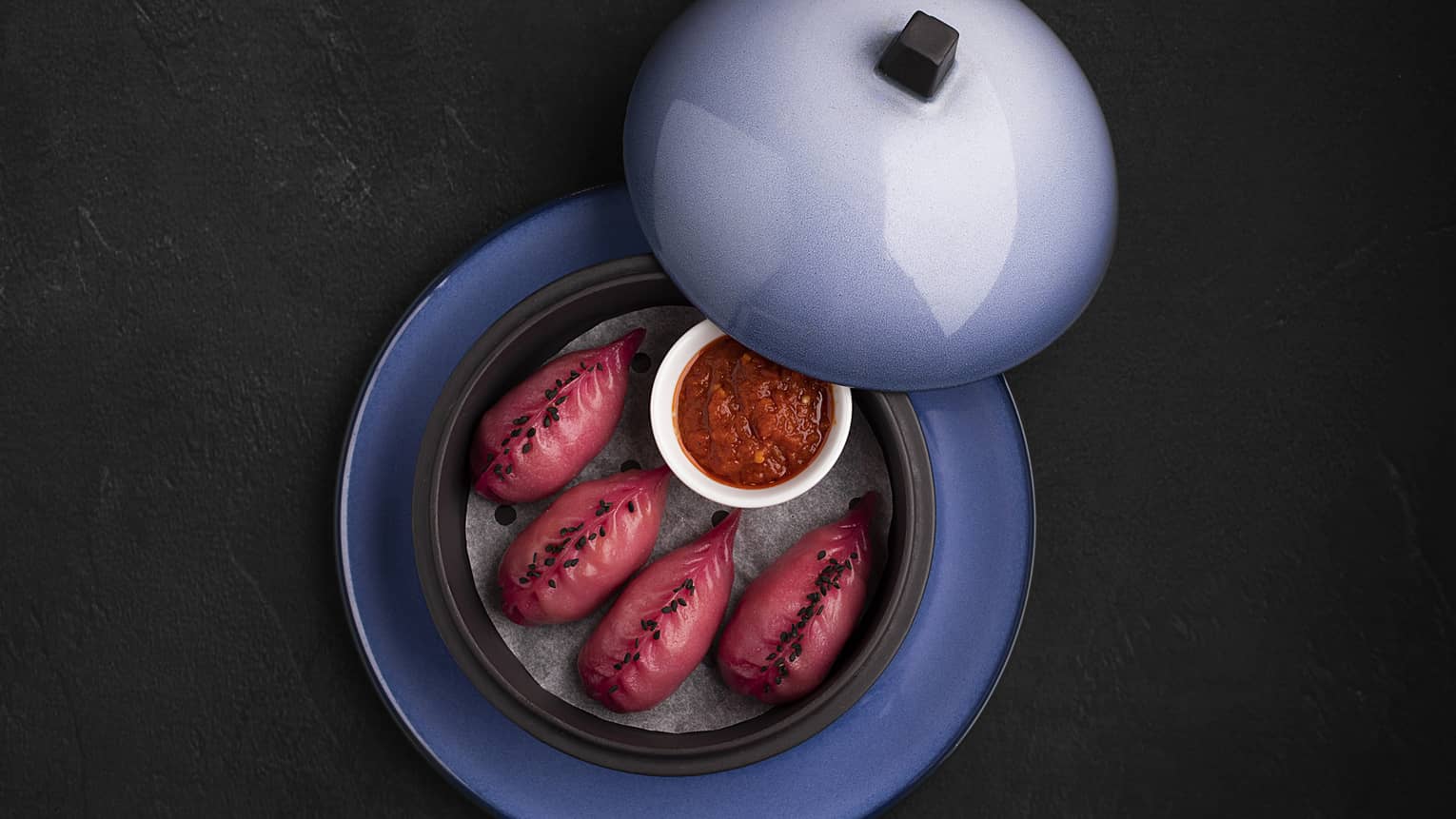 Lobster Dim Sum featuring lobster, yuzu and sambal sauce served in a light blue plate with a lid