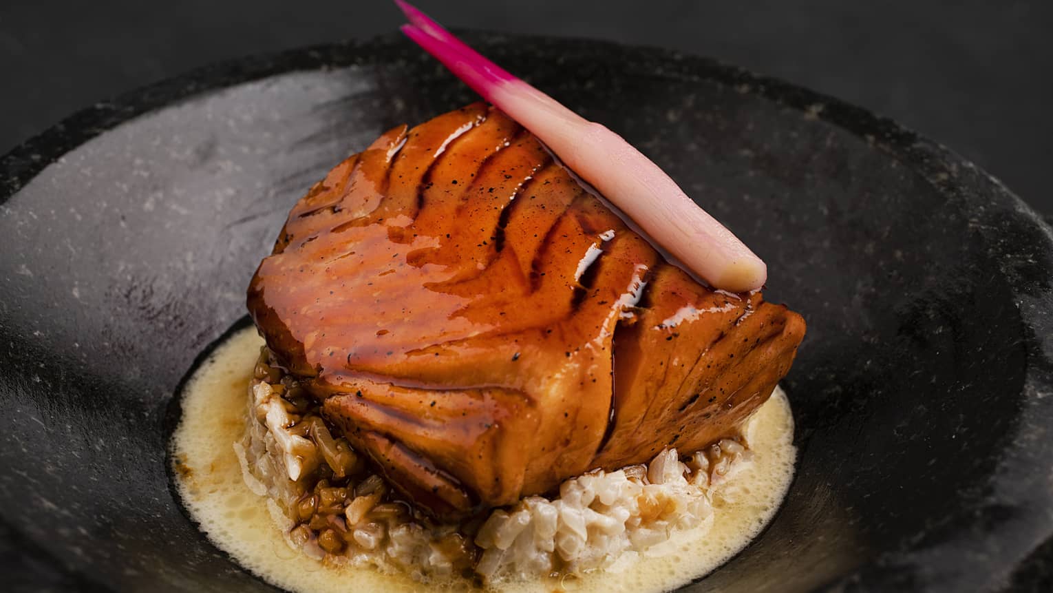 Salmon Teriyaki served atop creamy bean sprouts with teriyaki sauce in a black round bowl