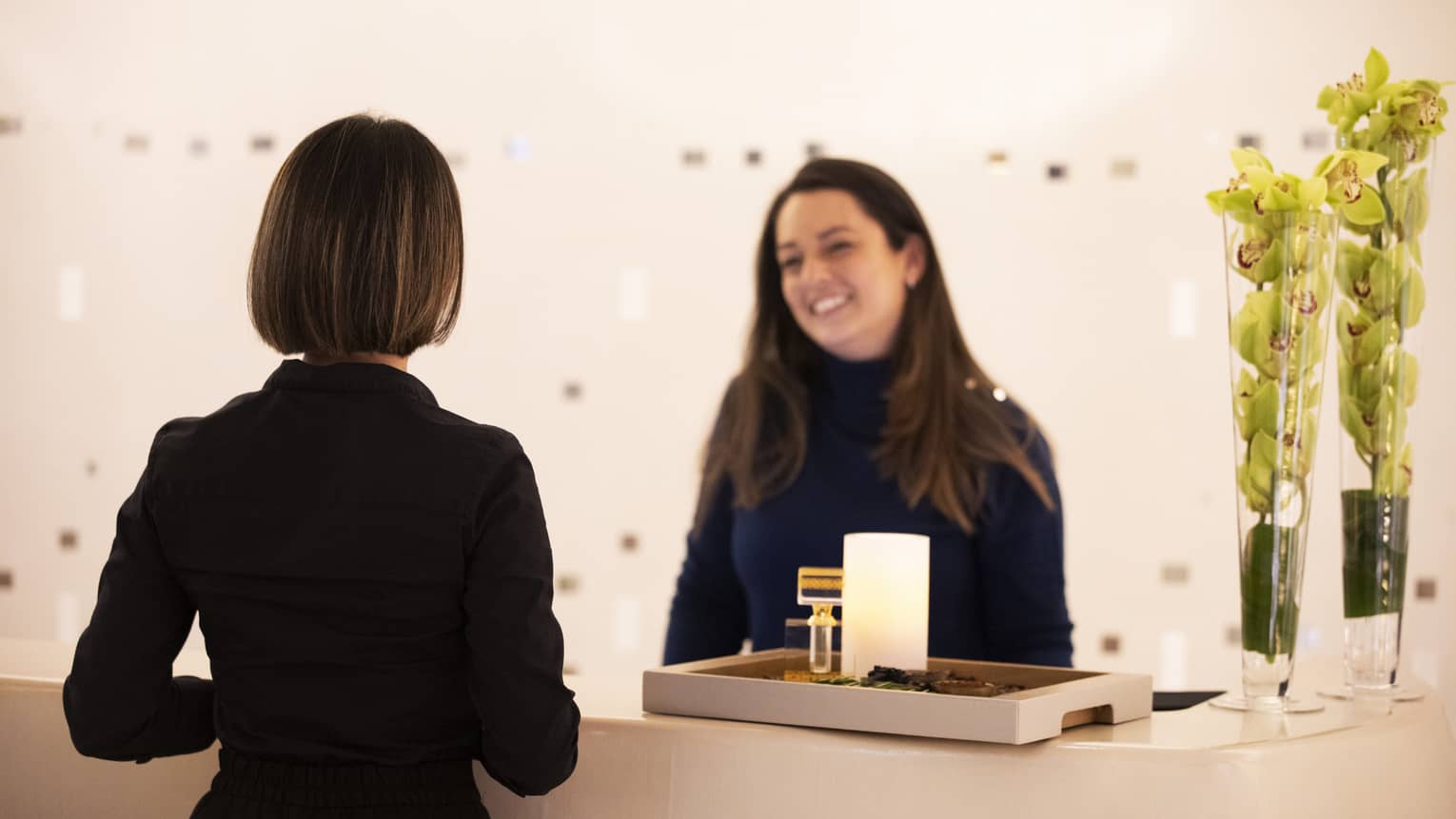 Woman greets another woman at spa reception counter
