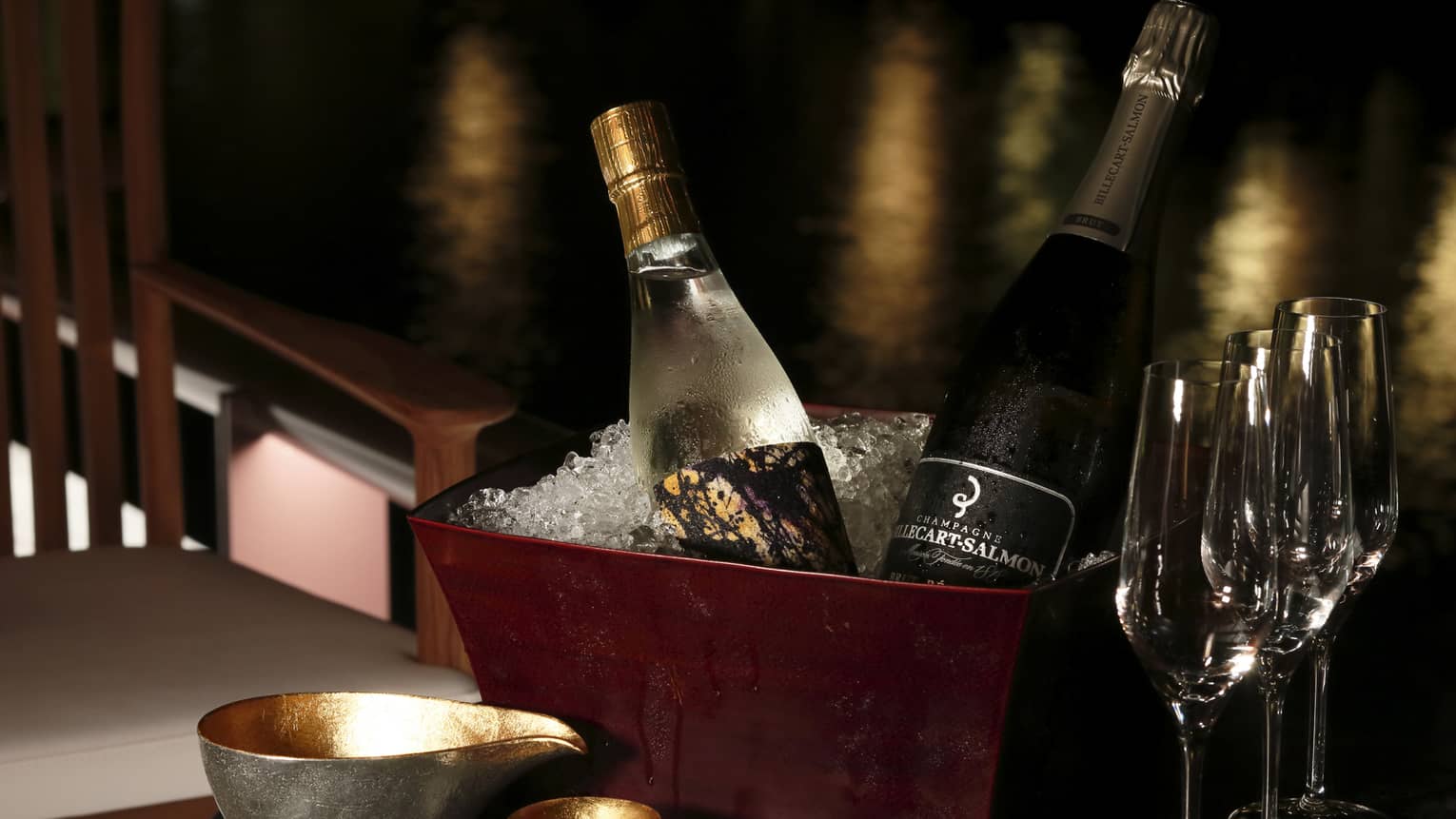 Bottles of sake and Champagne in brown ice bucket on table with glasses