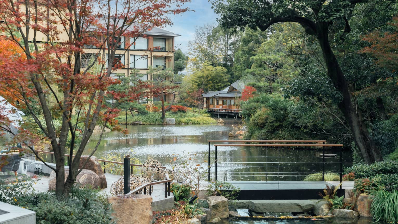 A pond surrounded by trees and crossed by a foot bridge