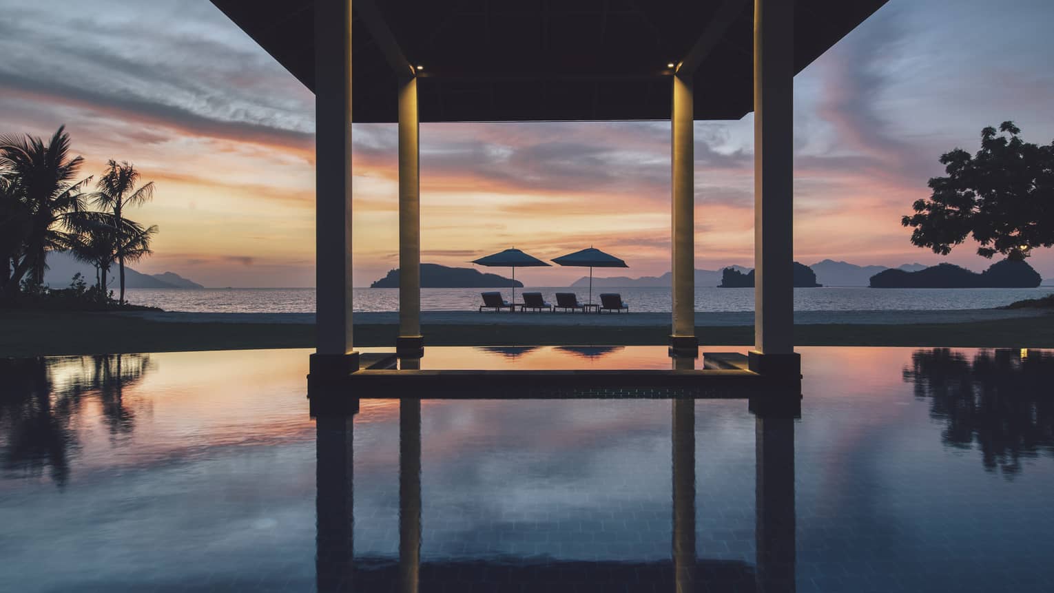 Infinity pool at desk, with orange and purple sky and beach view