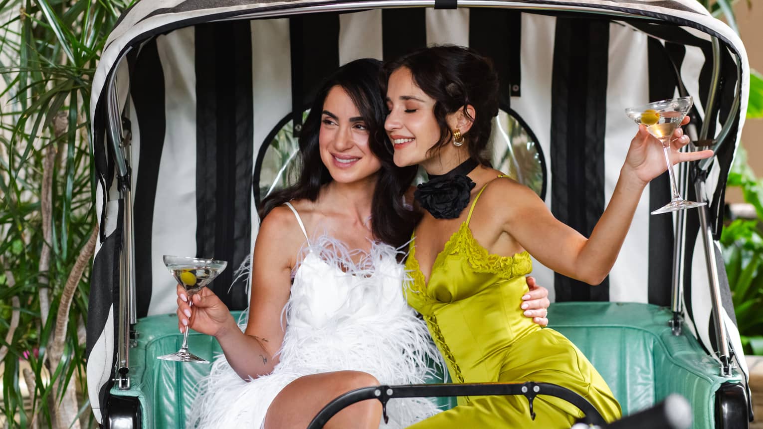 Two women pose for photo while holding Martini glasses on a stylish Tuk Tuk