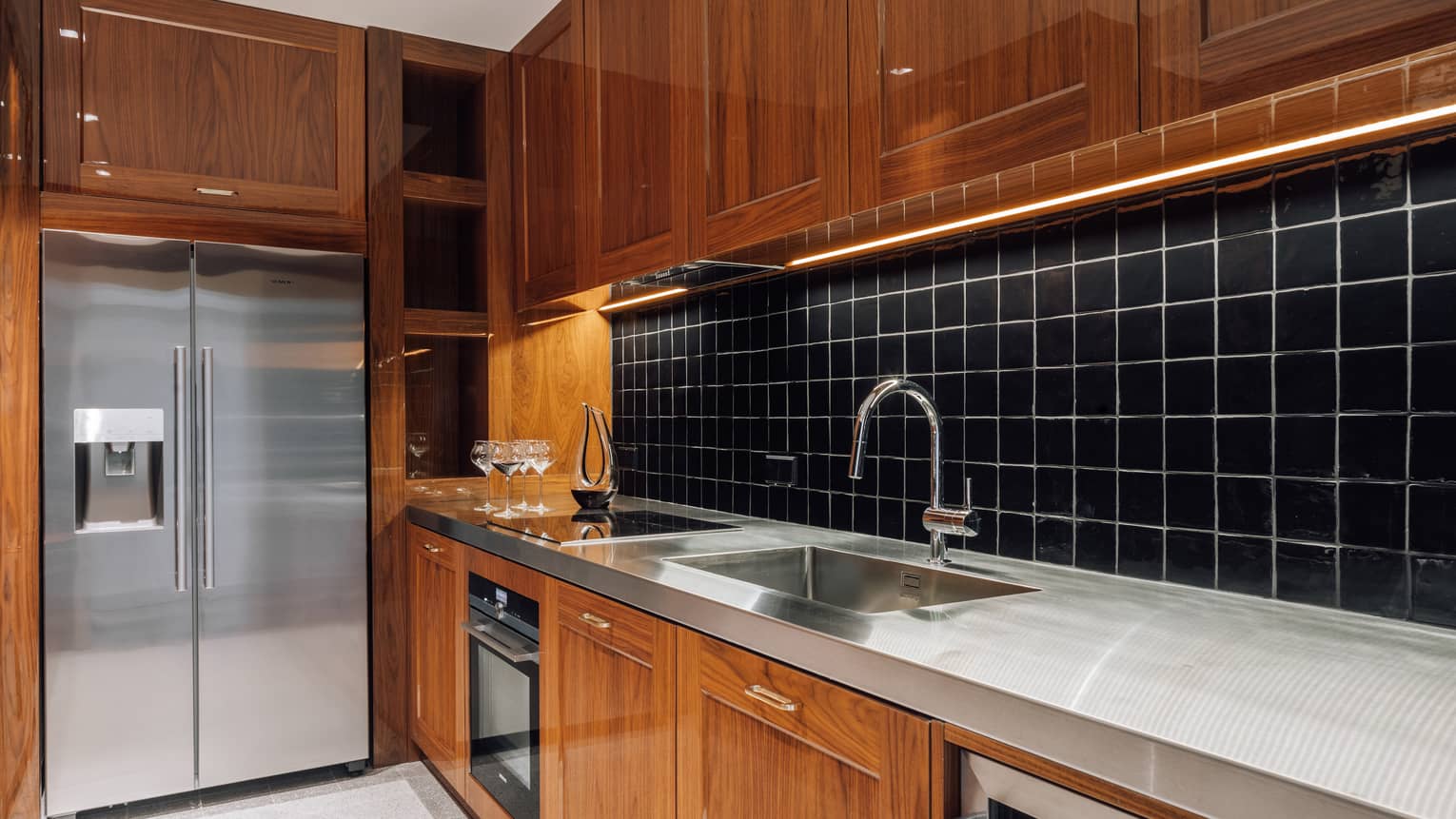 Kitchen with wooden cabinets, black tile backsplash, metal counter
