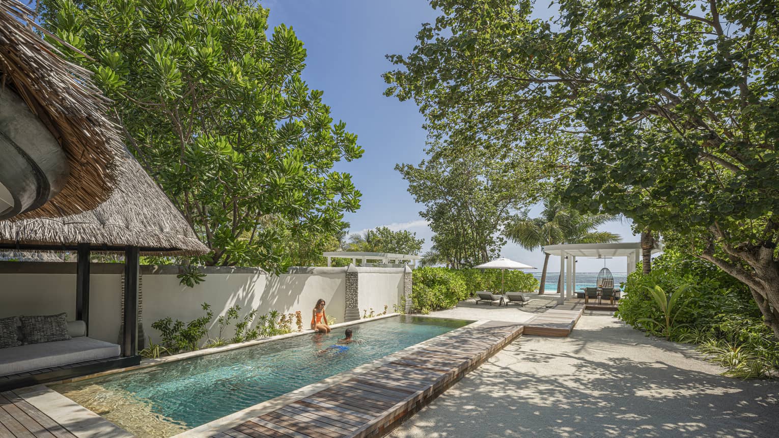 Private rectangular pool in a tropical villa setting with ocean in the distance
