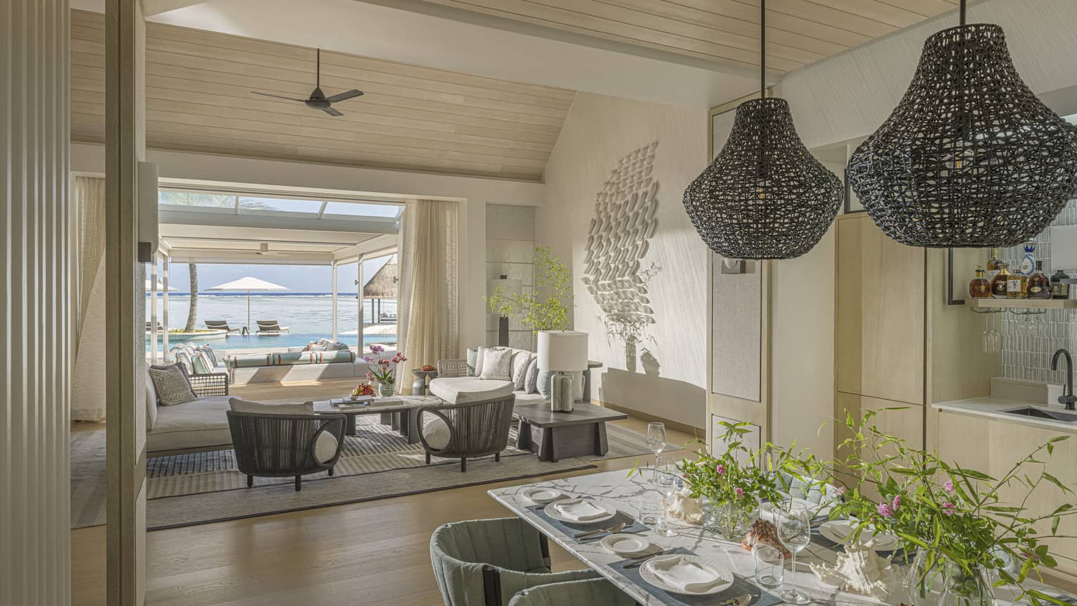 Interior of stylish luxury beachfront villa, featuring a dining room and living room opening to pool terrace