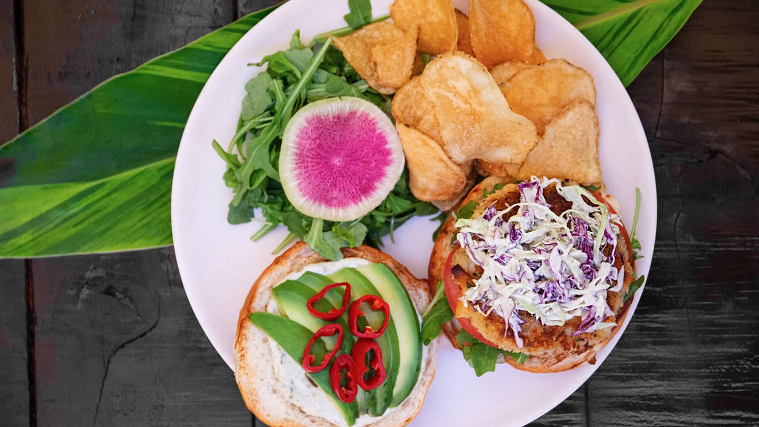 Crab cake sandwich with potato chips and radish salad
