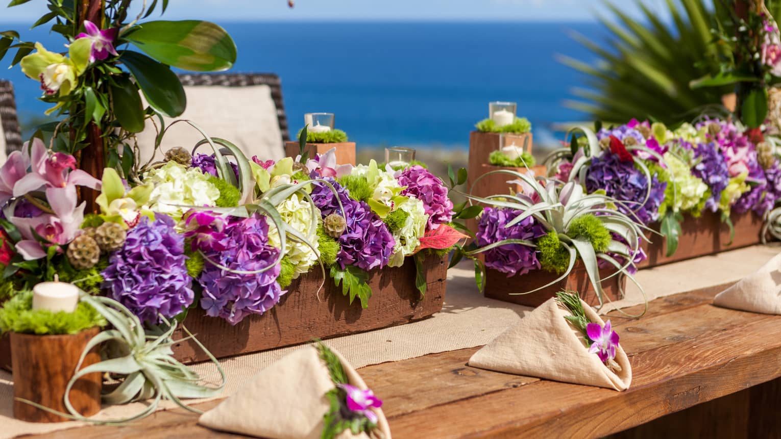 Long floral wedding centerpieces are set on a table overlooking the ocean in Lanai Hawaii