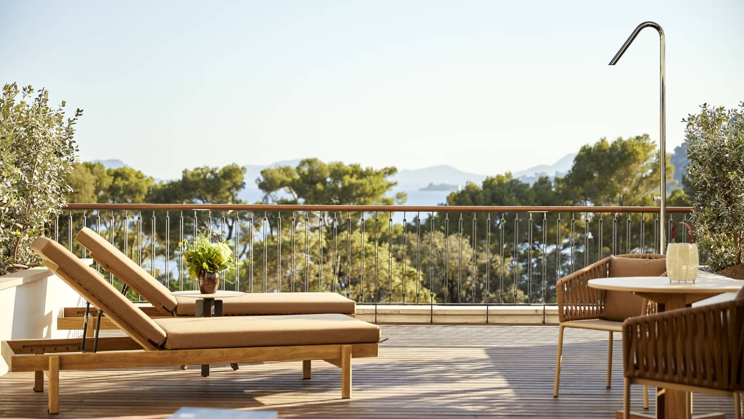 Private terrace of luxury hotel room at Four Seasons Resort Mallorca, with two lounge chairs and a round dining table with two chairs