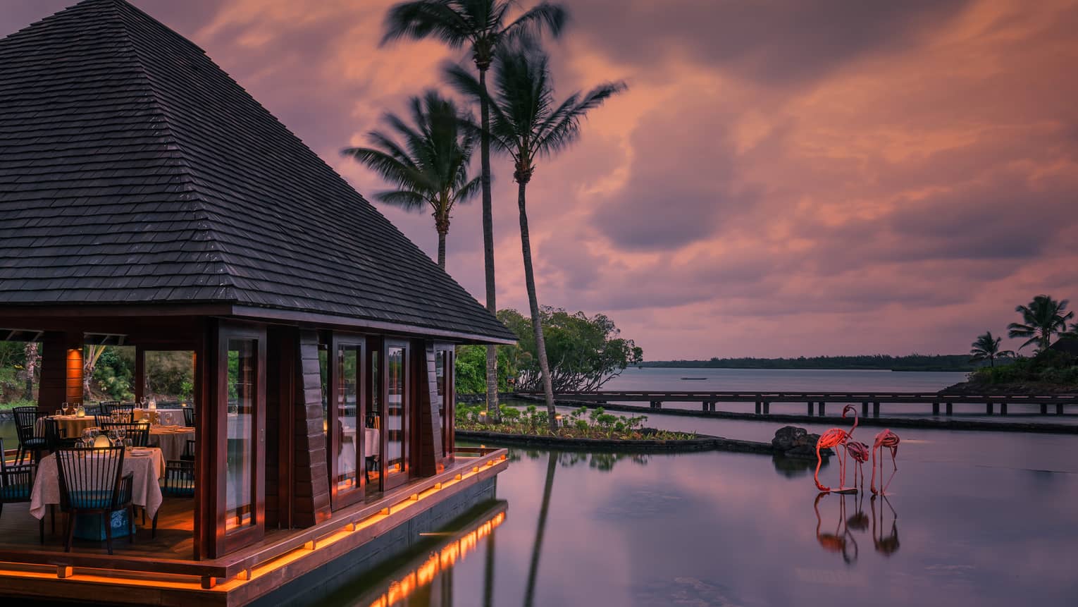 Beau Champ restaurant pavilion at sunset, two pink flamingo sculptures in water
