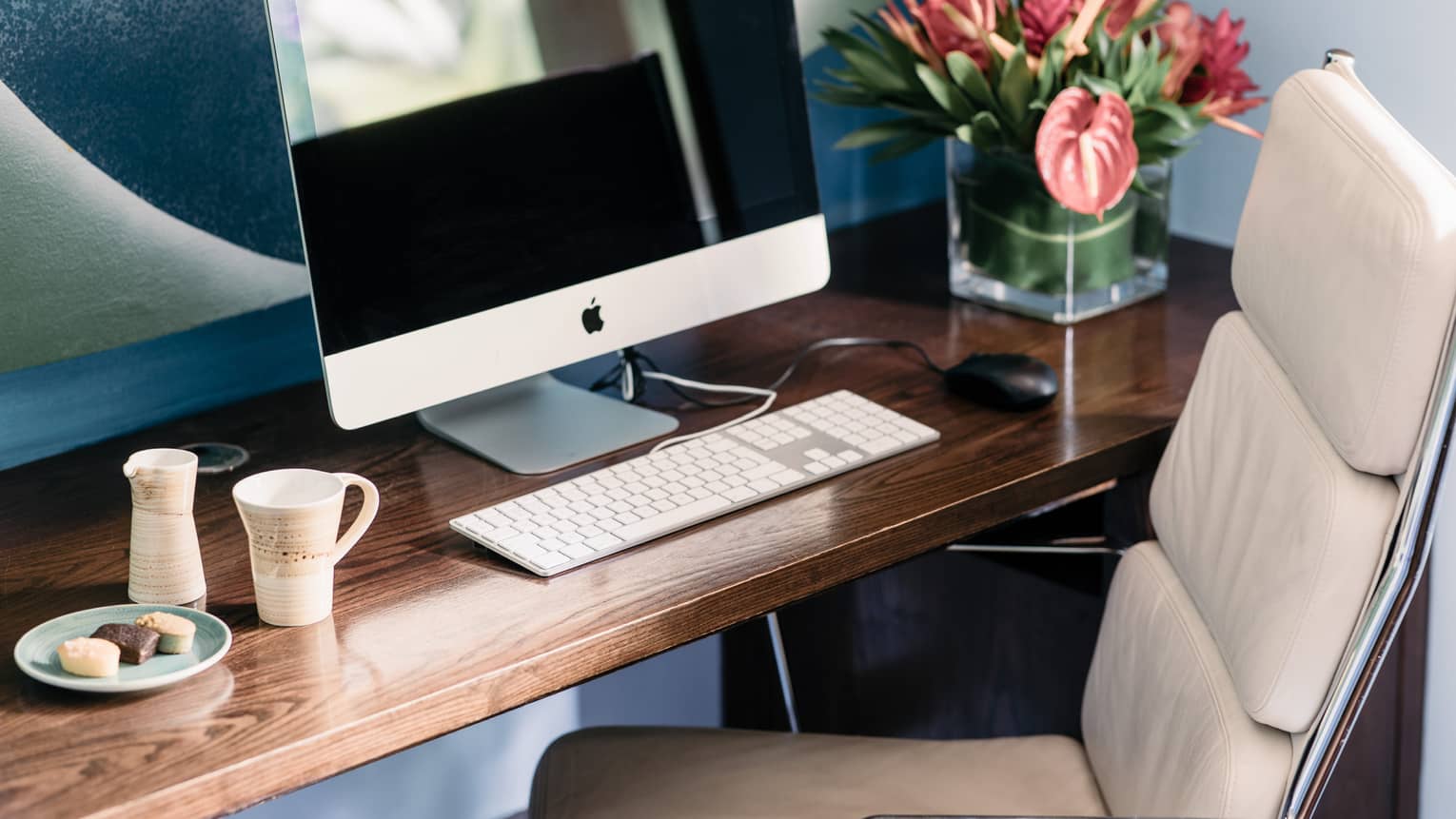 Computer and keyboard on wooden desk with white leather desk chair