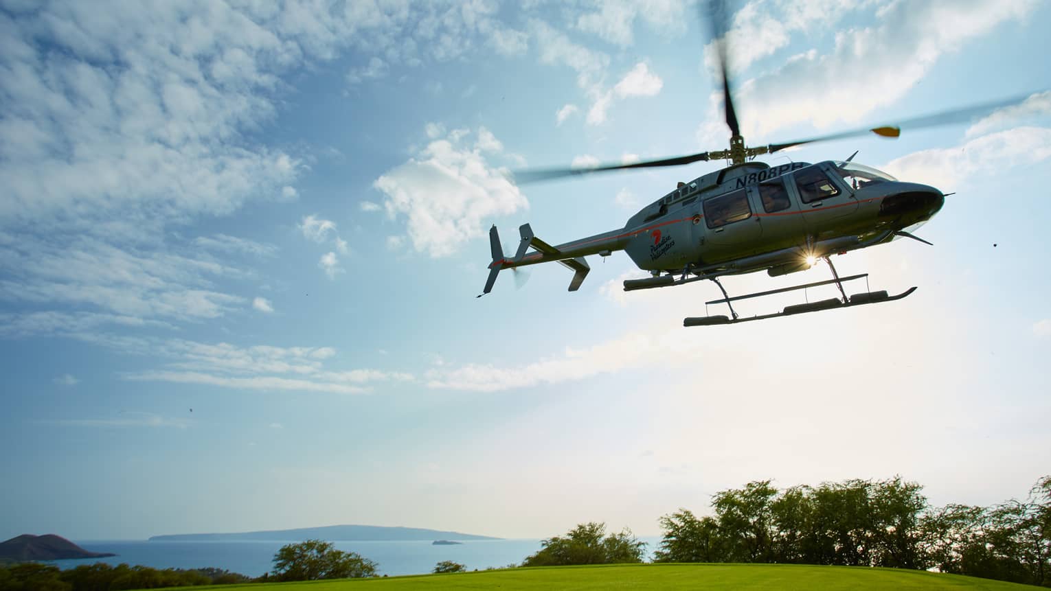 Helicopter hovers over green lawn under blue sky