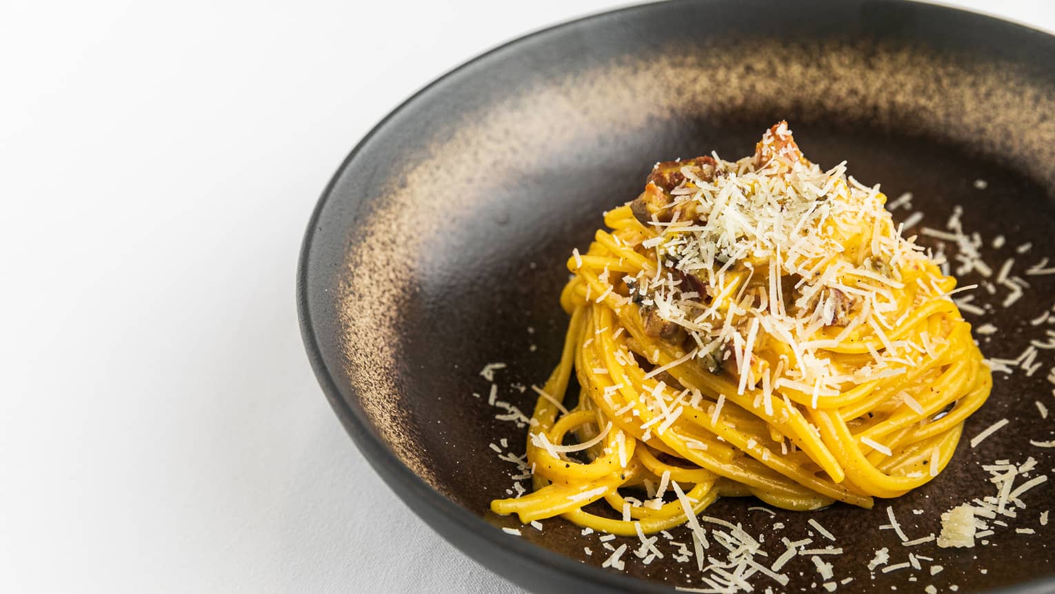 Noodles in a bowl with cheese sprinkled on it.