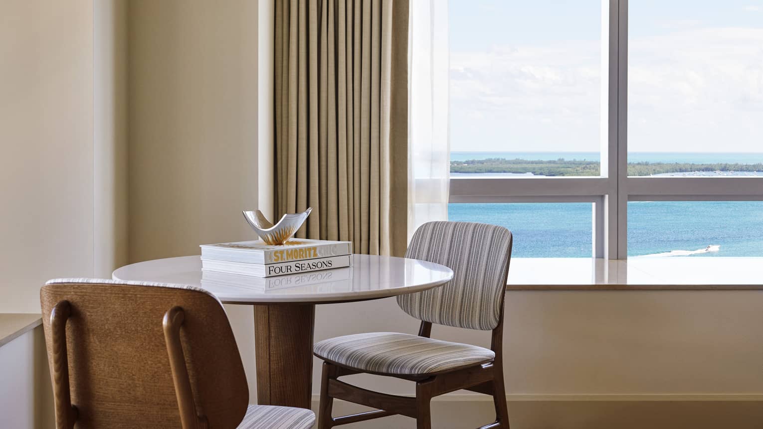 Round table with two chairs next to a bay-view window