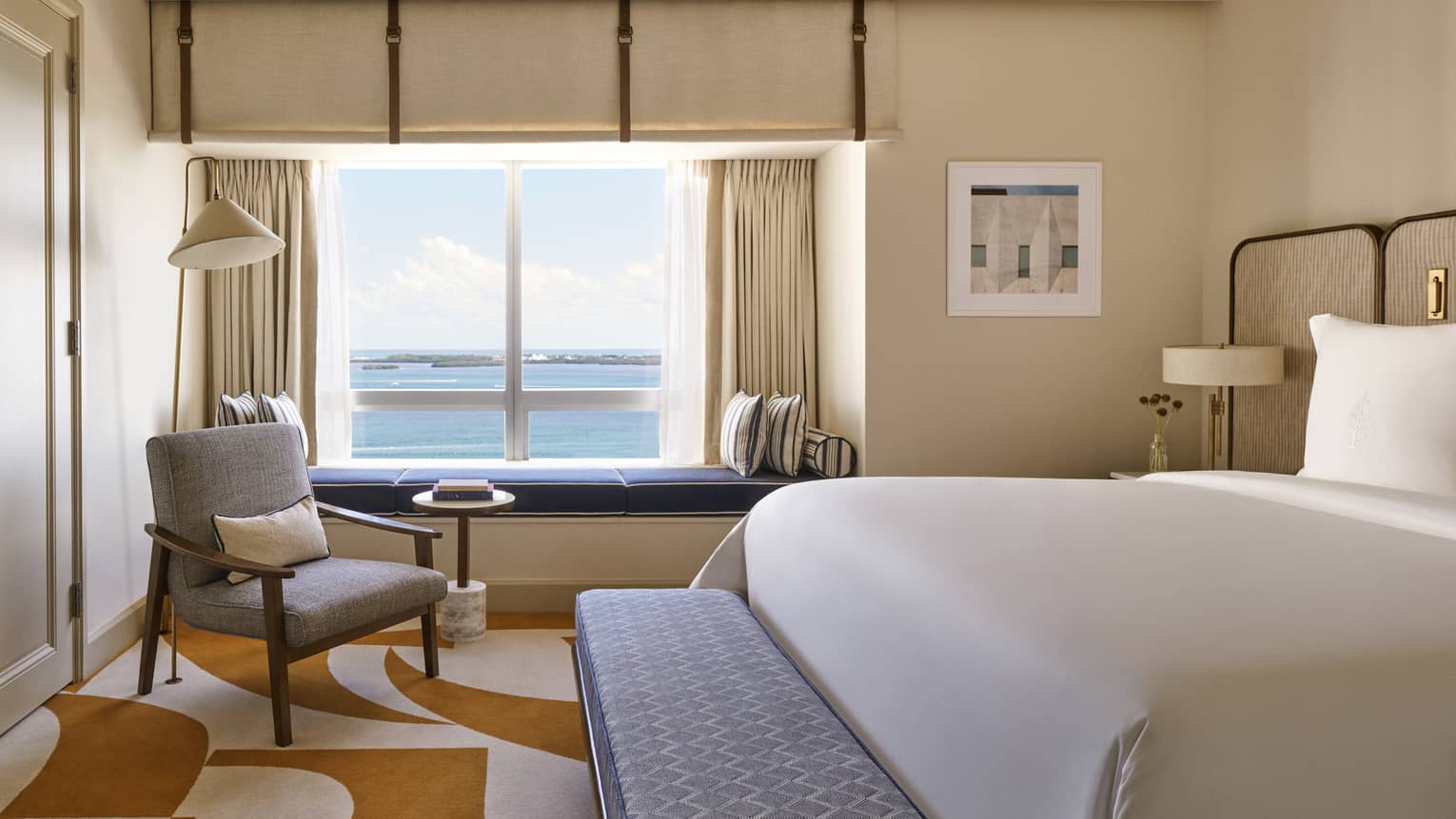 Hotel room with a king bed, bench, arm chair and built-in window bench