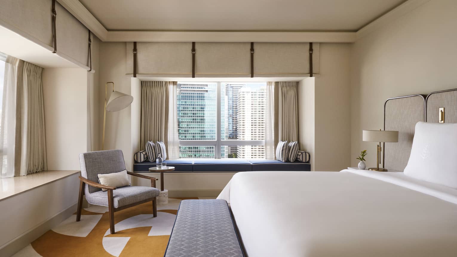 Hotel room with king bed, bench, arm chair and built-in window bench