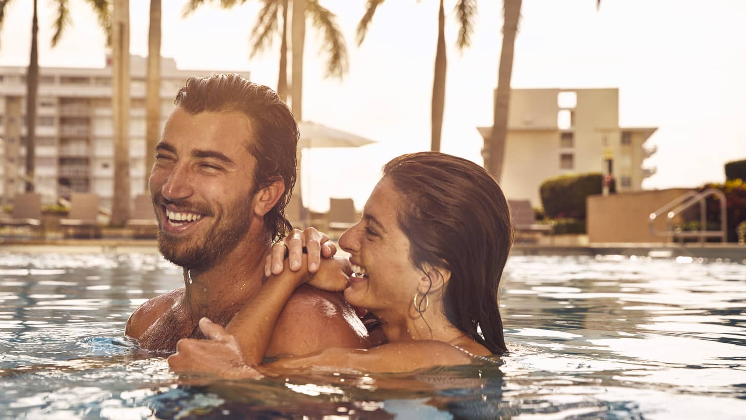 Man and woman laugh in pool