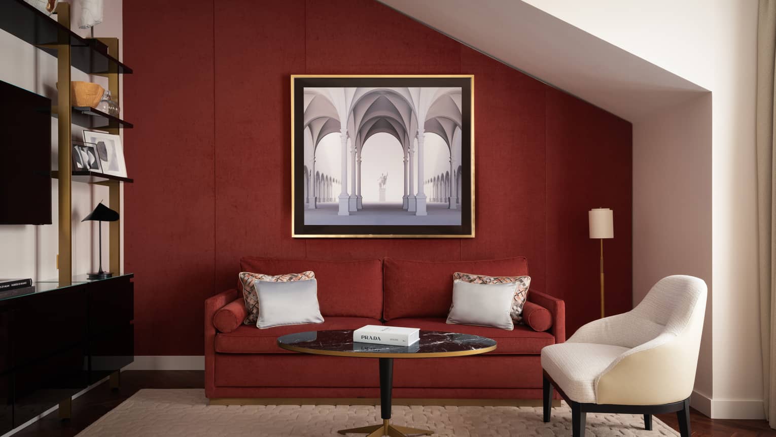 Sitting room featuring a dark red sofa and matching accent wall, plus a white arm chair