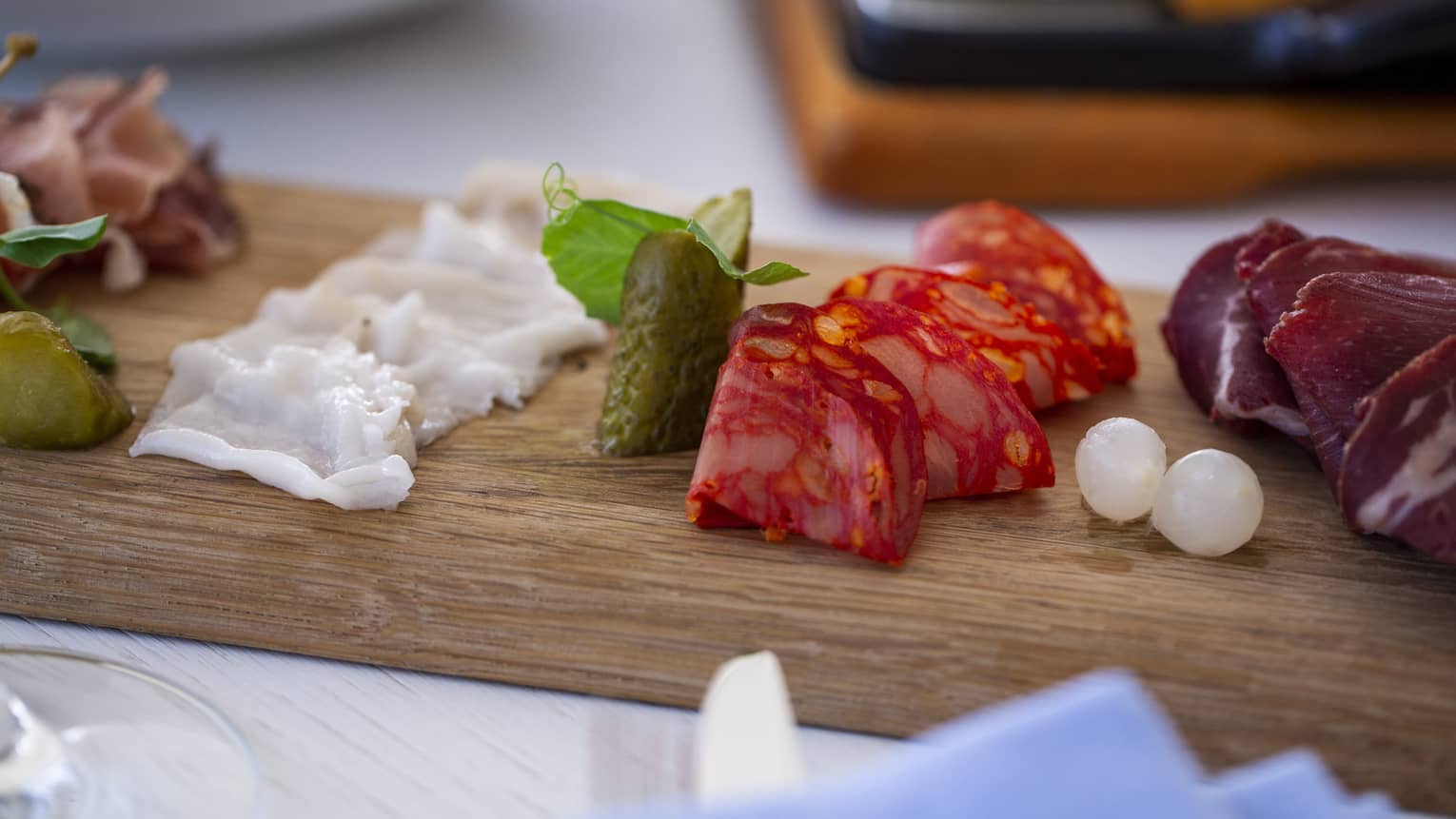A charteurtie board with salami, cheese and onions on a table