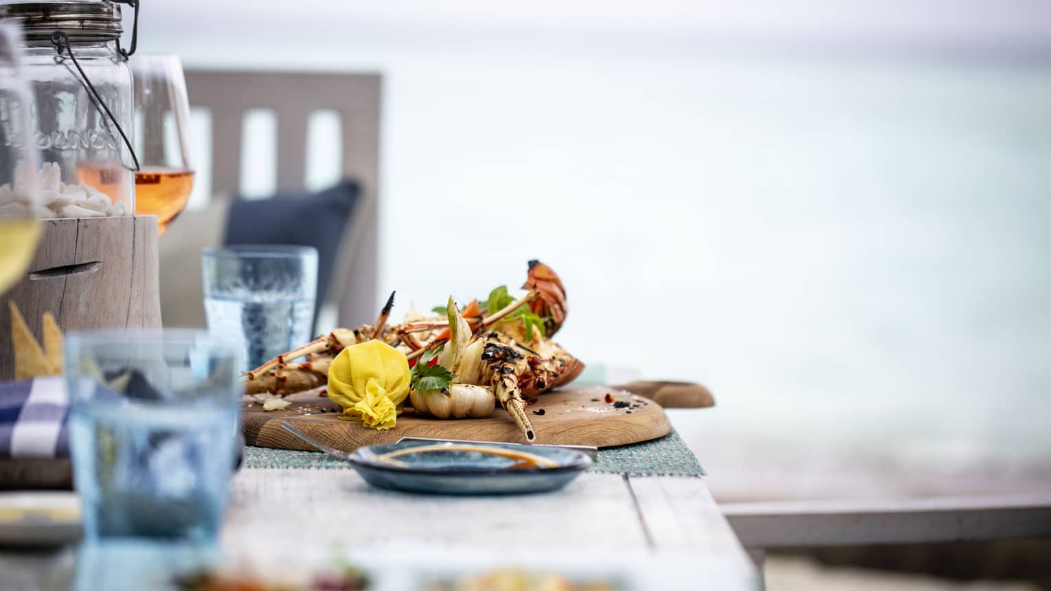 A tastefully set table with a glass of rose and a chicken dish overlooking the ocean at Fuego Grill