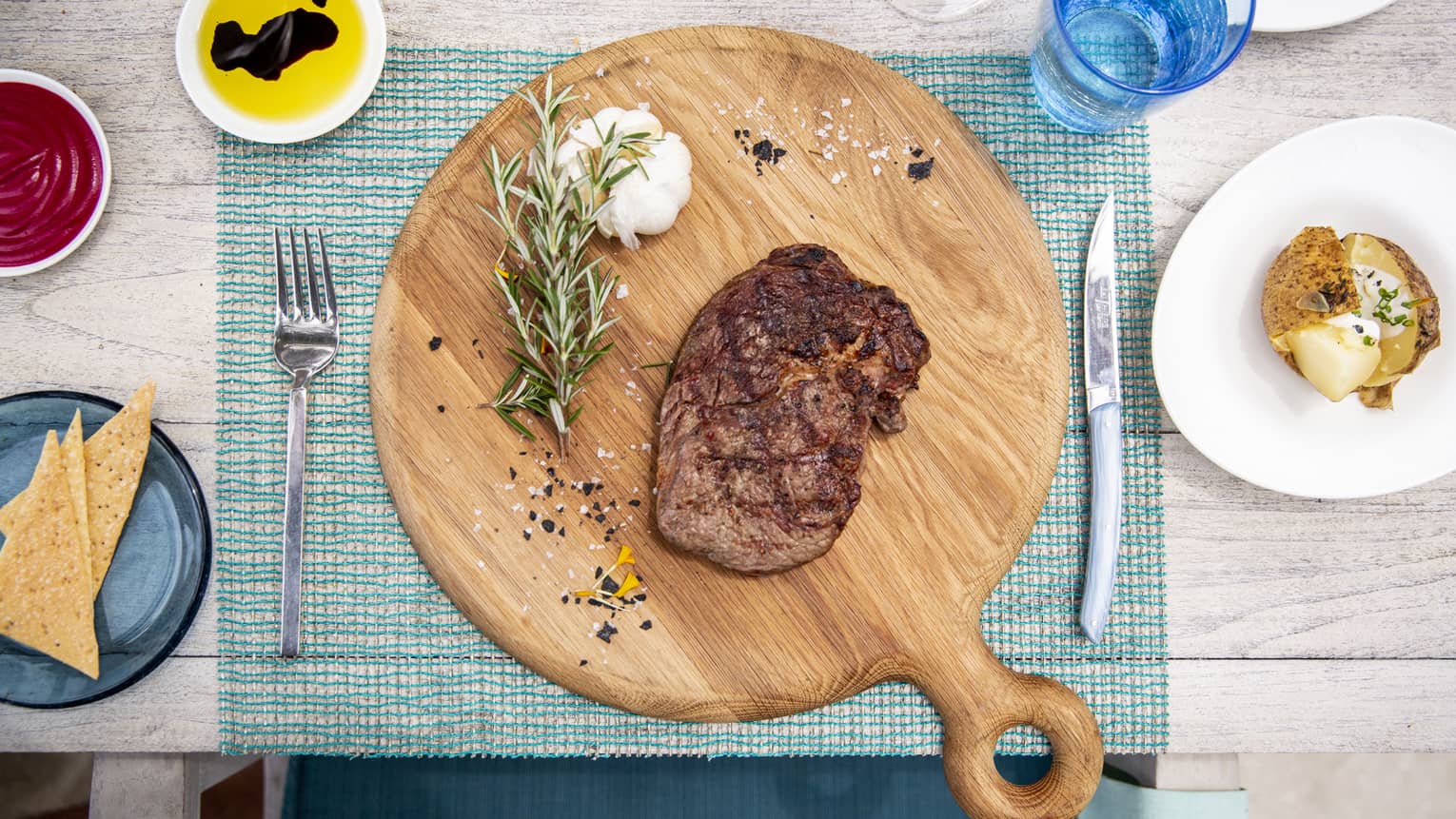 An aerial view of a table with a wooden board with a beef dish and garlic and rosemary at Fuego Grill