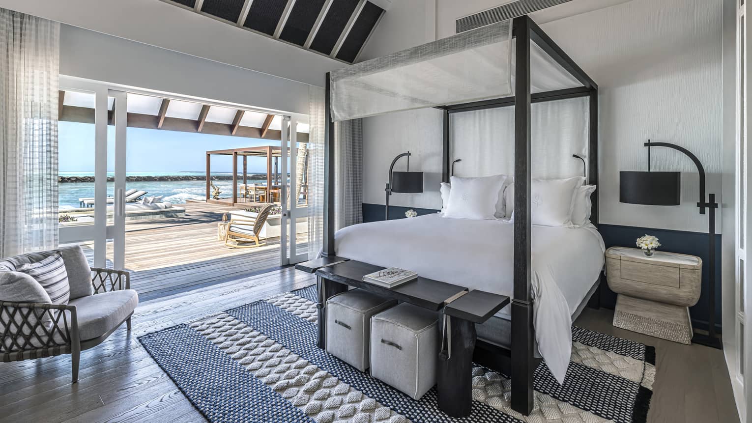 Bedroom with four-poster bed, doorway opening on to deck with pool and cabana