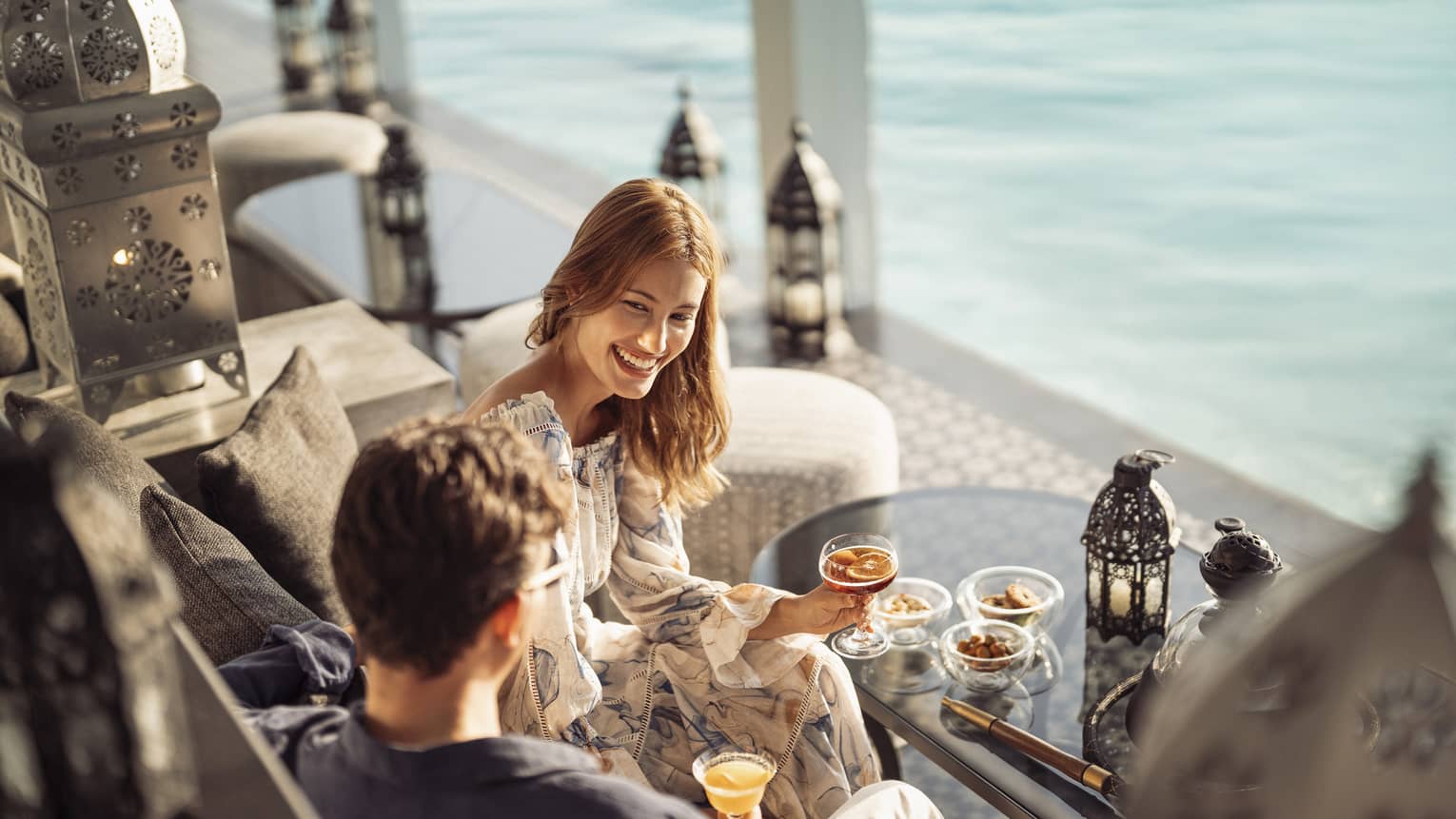 Smiling couple enjoys cocktails on the outdoor terrace of Al Barakat