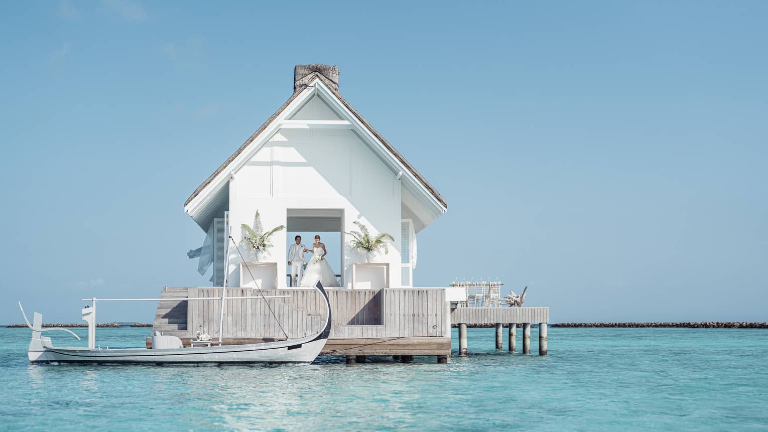 Bride and groom emerge from their overwater wedding pavilion