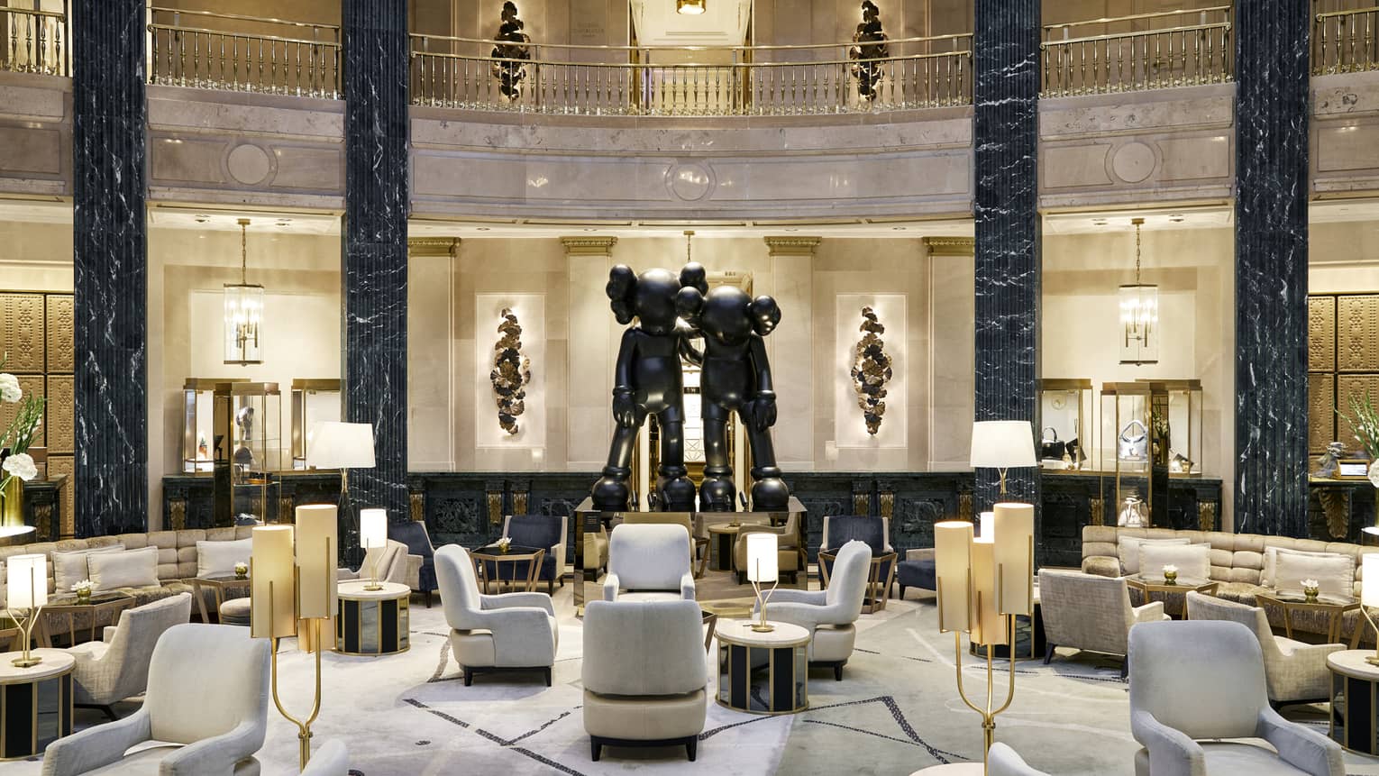 A spacious hotel lobby with a large seating area, black marble columns and a statue