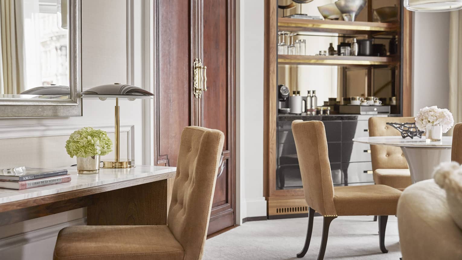 Desk with lamp and light brown chair, and round table with four chairs in the background