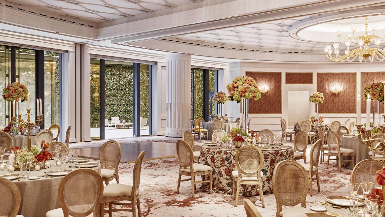 Several tables and chairs adorned with linens, flowers and glassware.