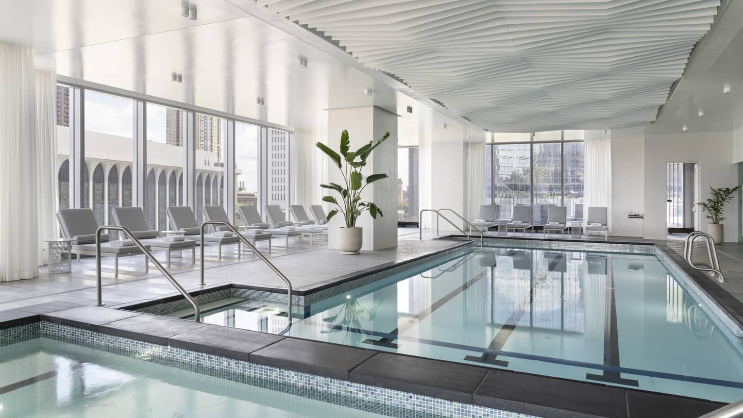 An indoor pool surrounded by lounge chairs.