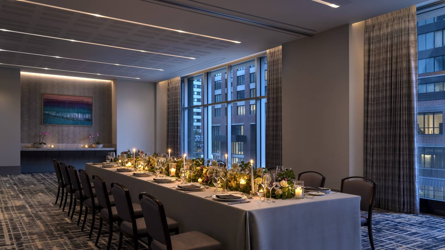 A long table with candles and flowers in a dimly lit room.