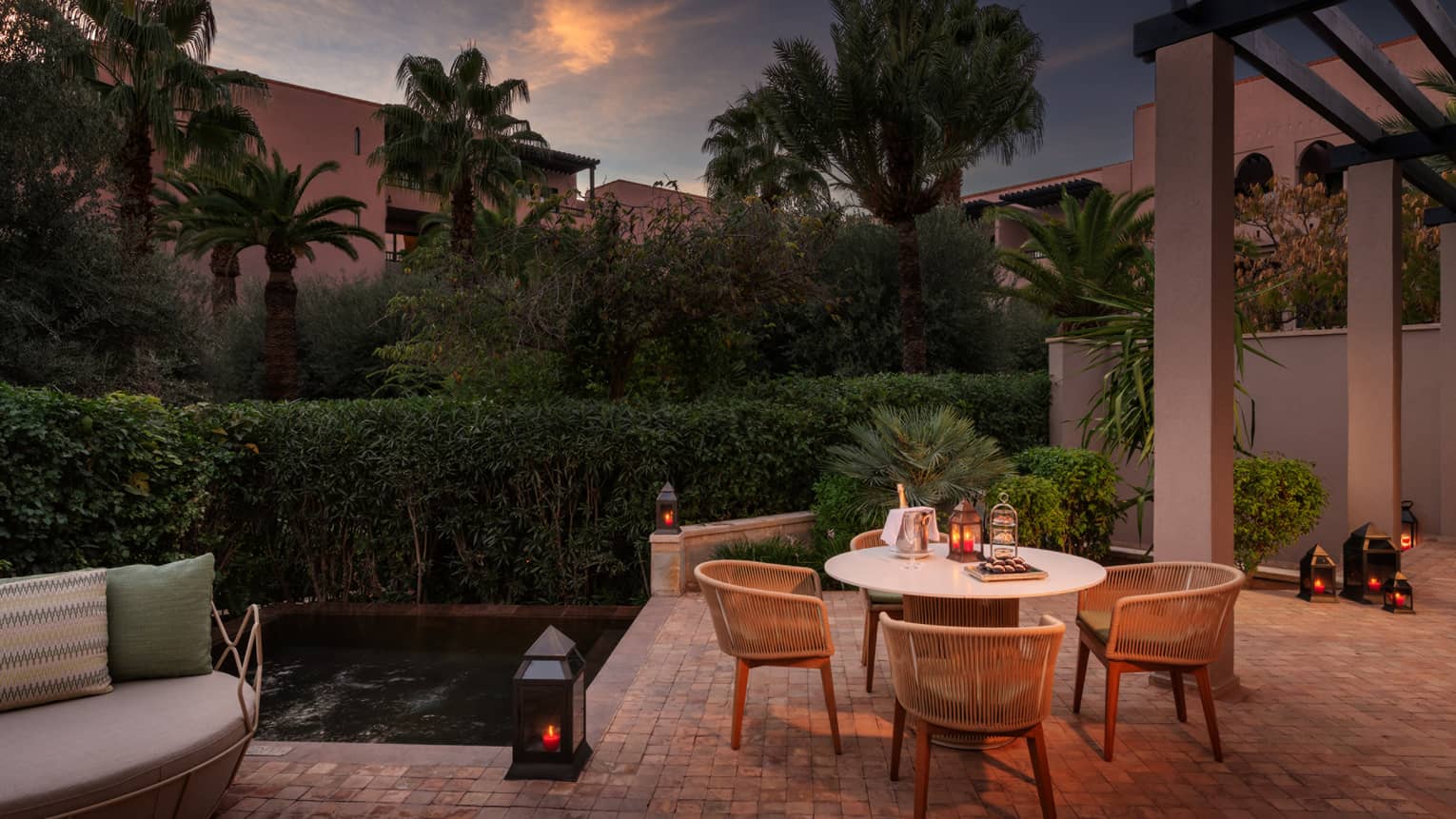 Hotel terrace at night, with dining table and gardens