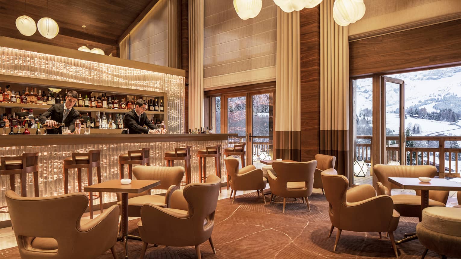 Bartenders mix drinks at Le 1920 bar by midcentury-style lounge chairs, tables, under soaring ceilings