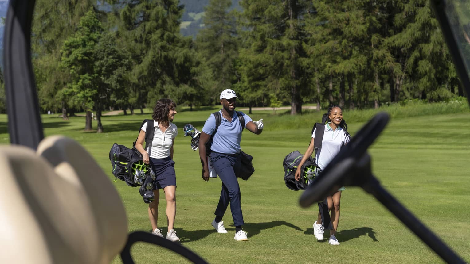 Three people on a golf course, carrying golf bags