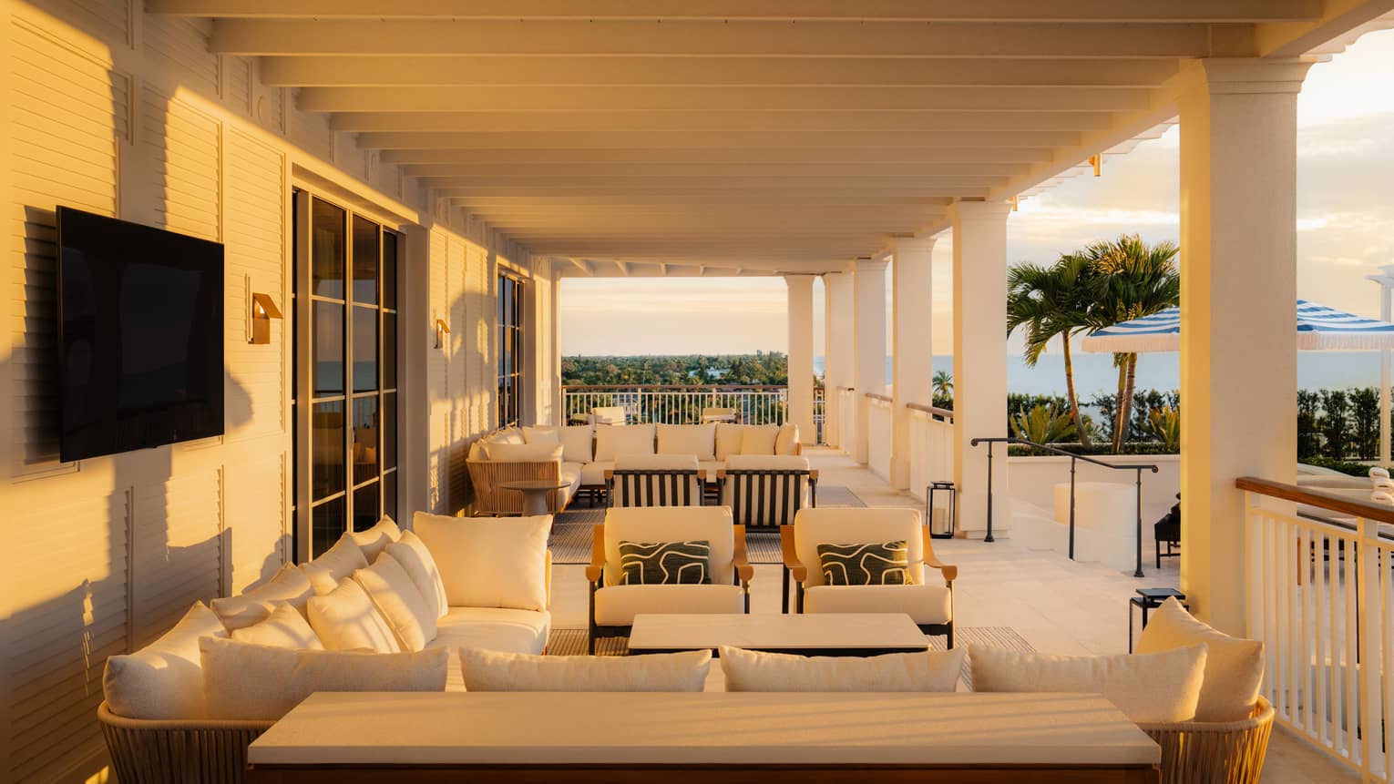 Large covered terrace at luxury resort, featuring lounge furniture, TV and ocean view