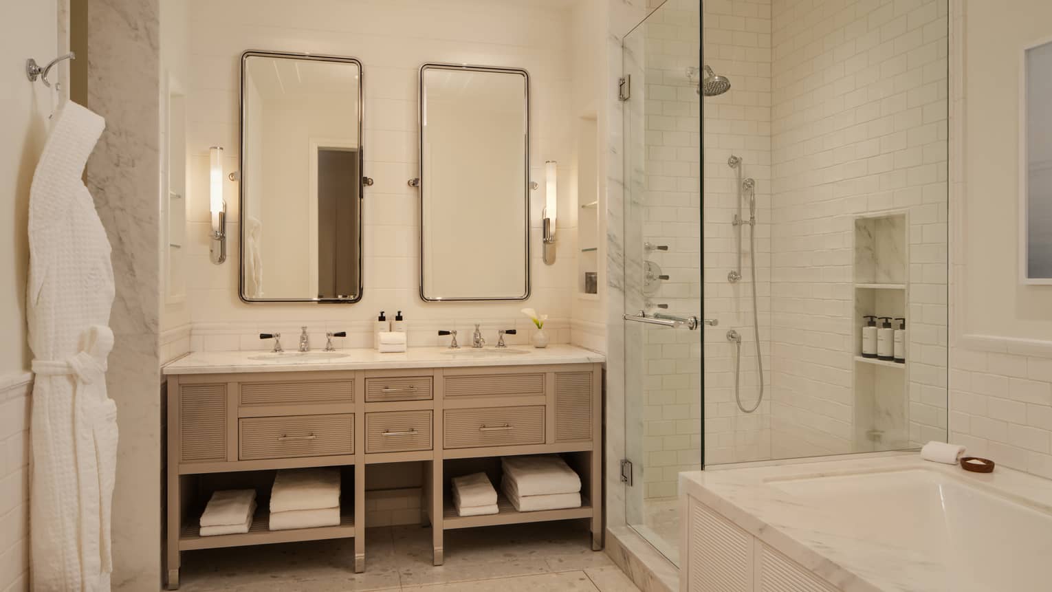Luxury hotel bathroom with double vanity, two vertical mirrors, walk-in shower and separate marble bath tub
