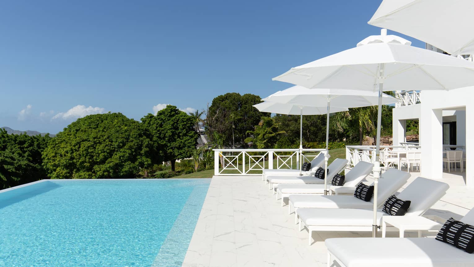 Private pool deck with six lounge chairs, four umbrellas and surrounding trees