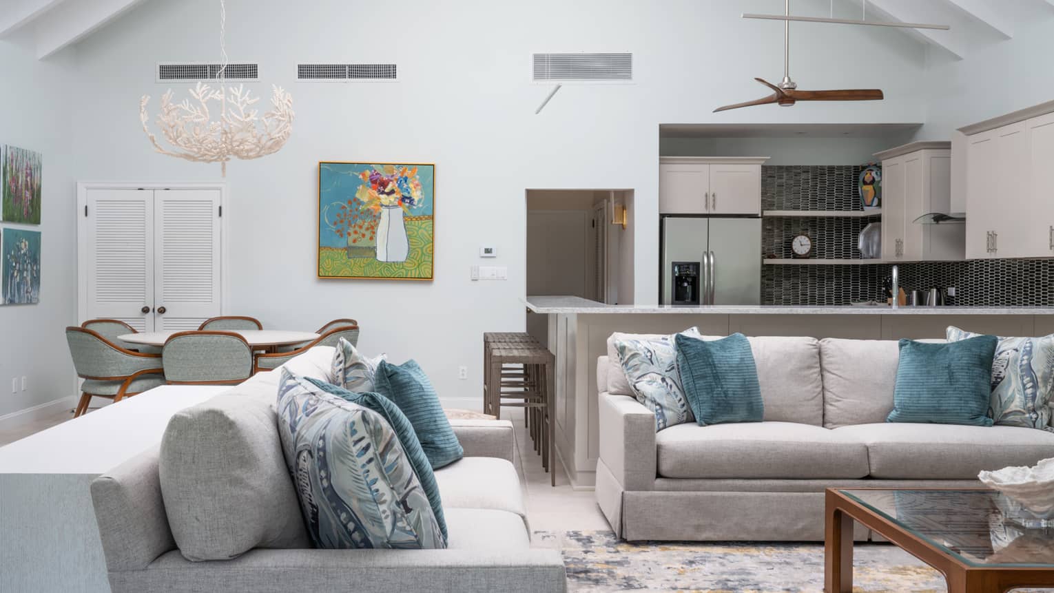 Living room with two grey sofas, kitchen with bar seating and round dining table