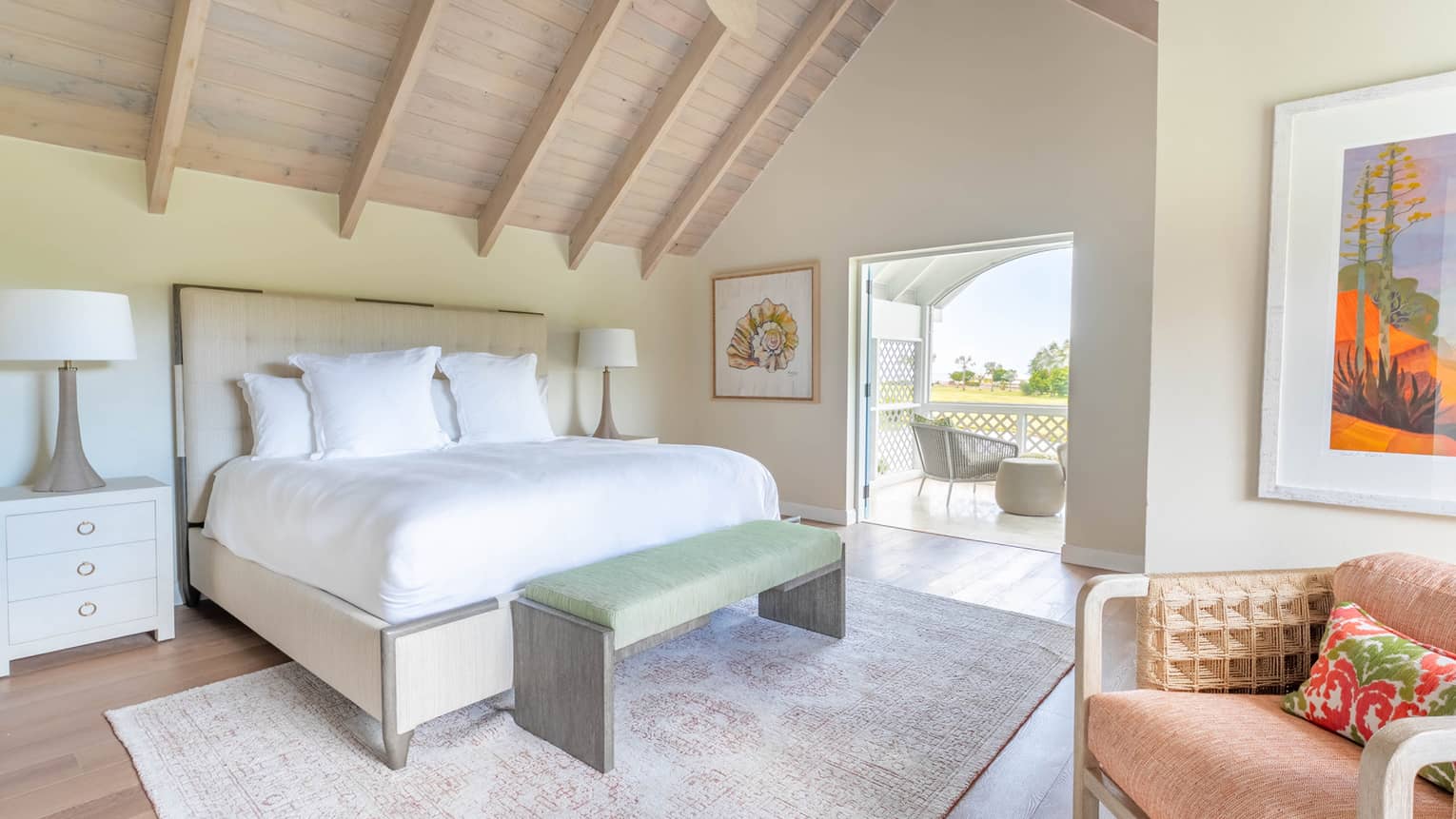 Bedroom with king bed, vaulted wooden ceiling, ceiling fan, bench, rug and walk-out terrace