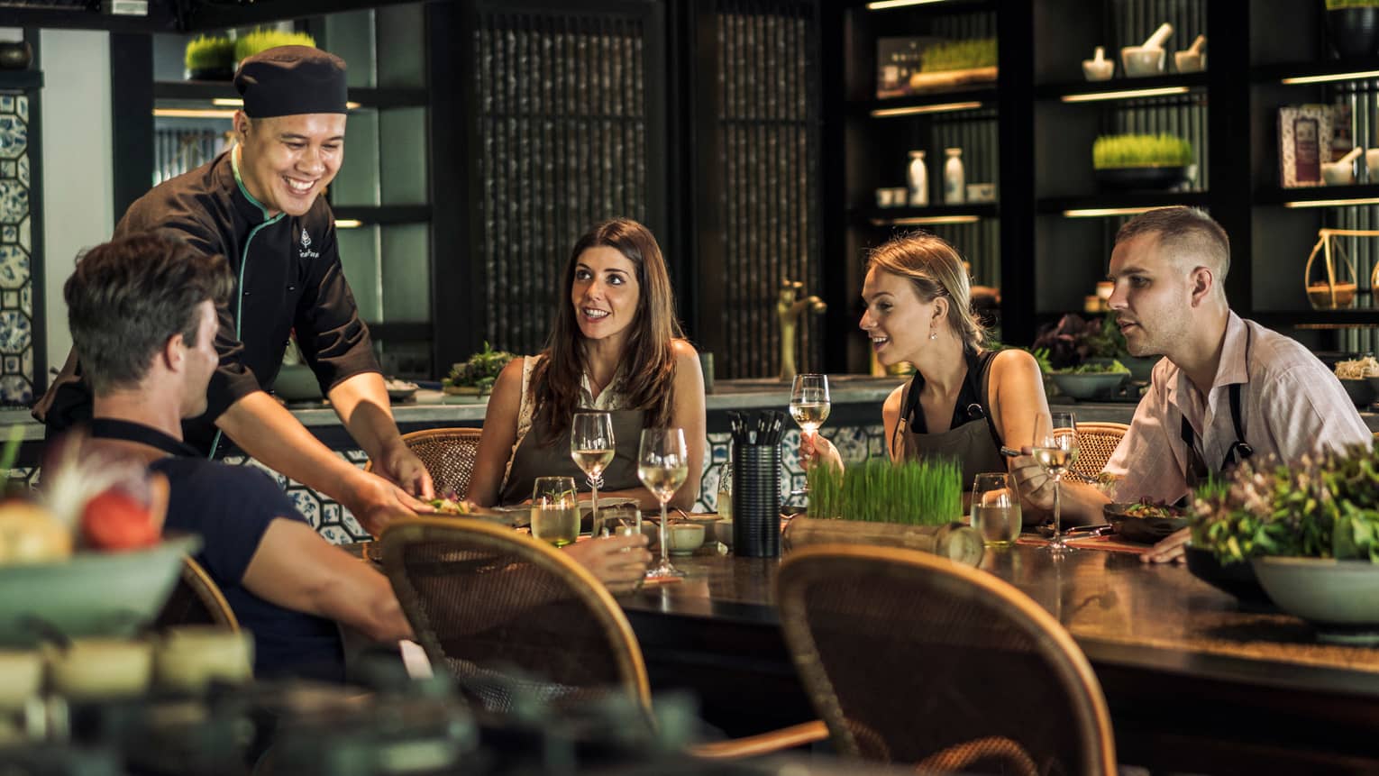 Smiling chef serves table of friends in La Sen dining room