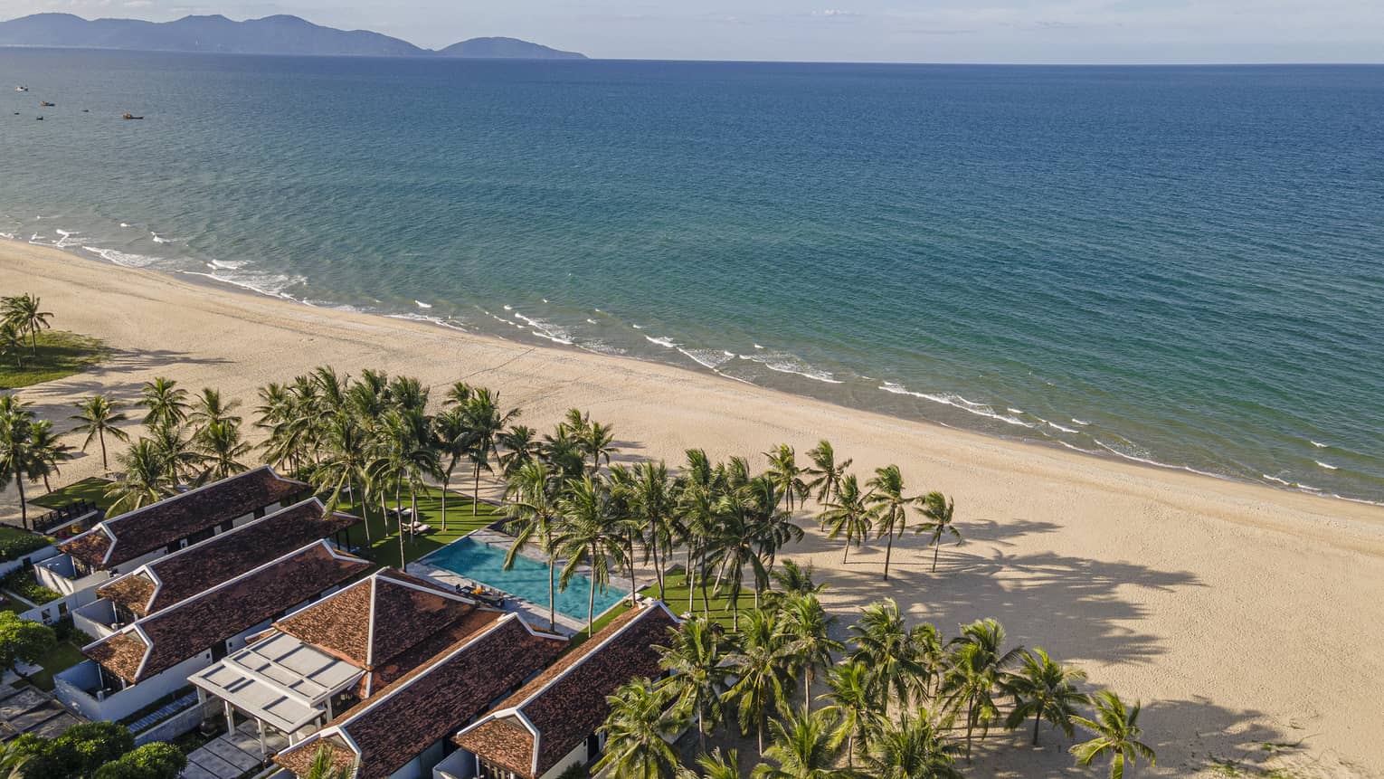 5 Bedroom Beachfront Pool Villa aerial shot with ocean and mountain views, palm trees and blue skies