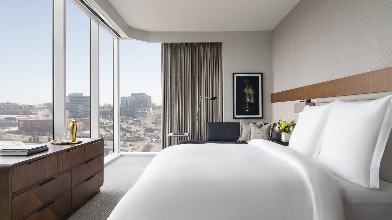 Hotel room with king bed looking out to corner-view wall of windows