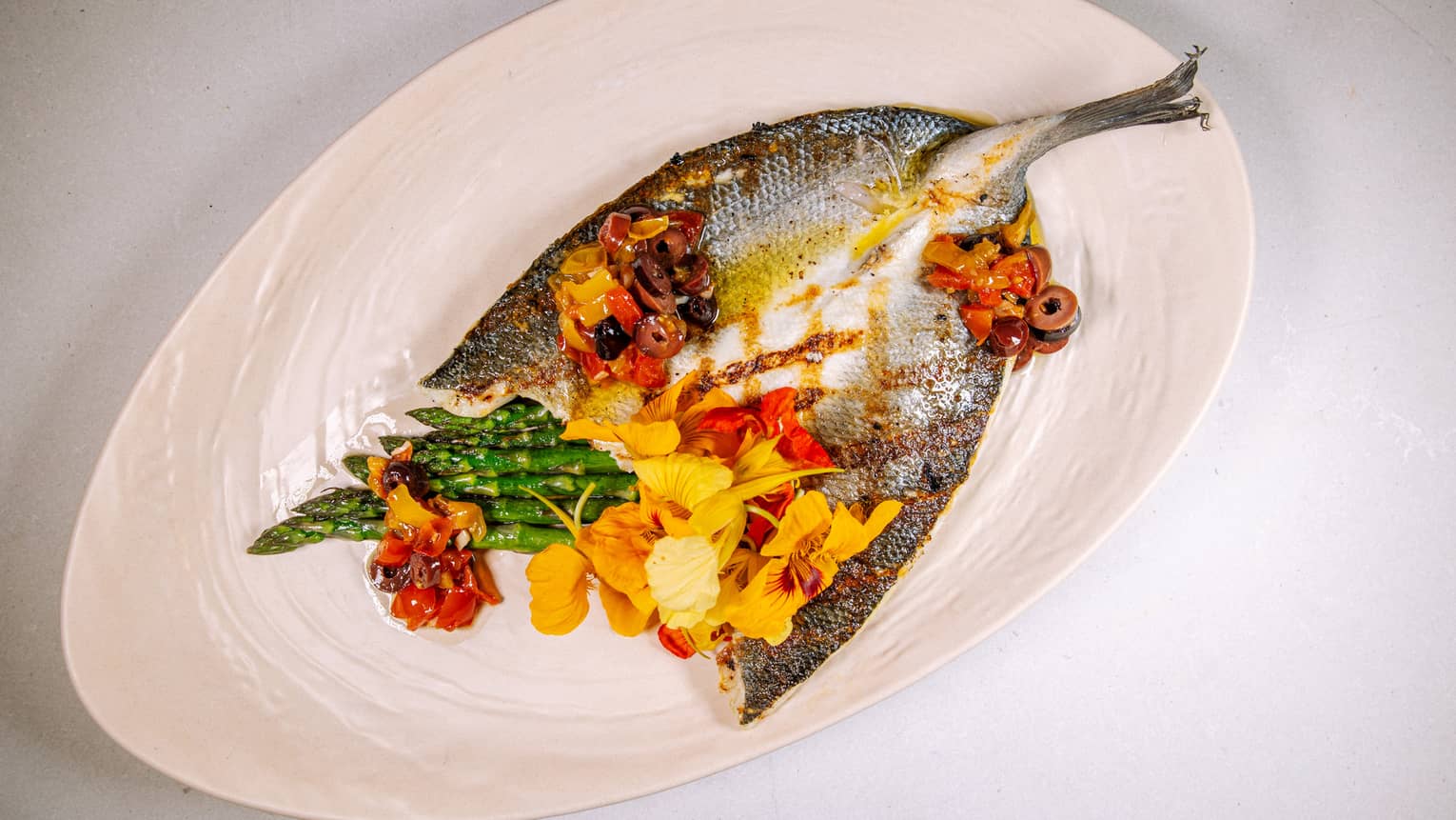 A large fish grilled with asparagus.