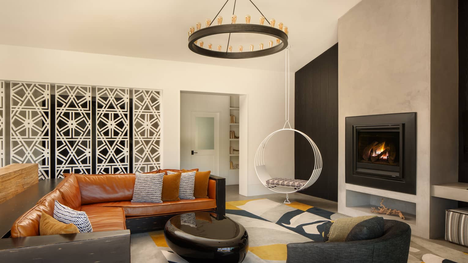 Modern living room featuring a leather sectional sofa, fireplace and circular hanging chair