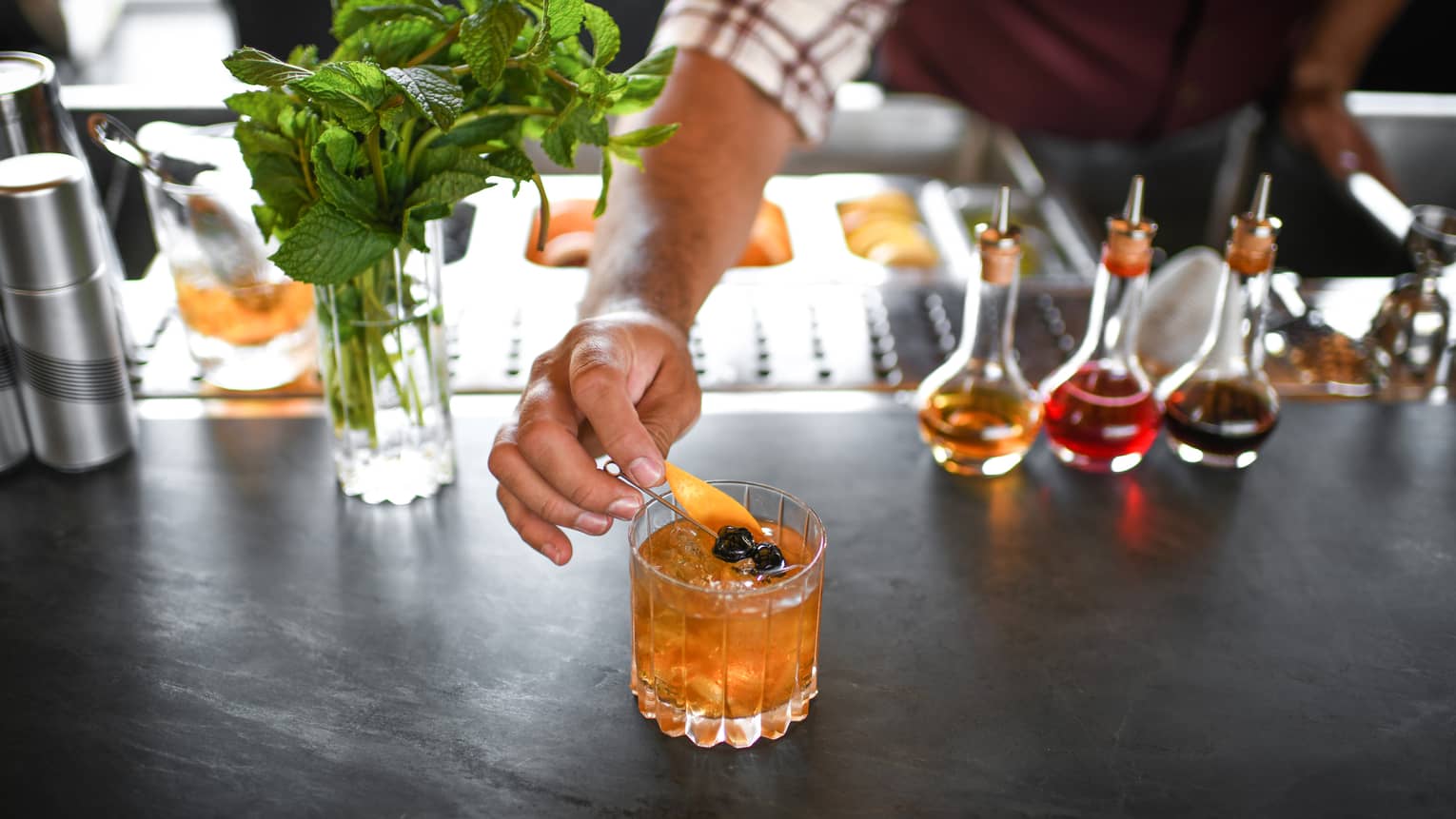An amber coloured cocktail next to garnishes.
