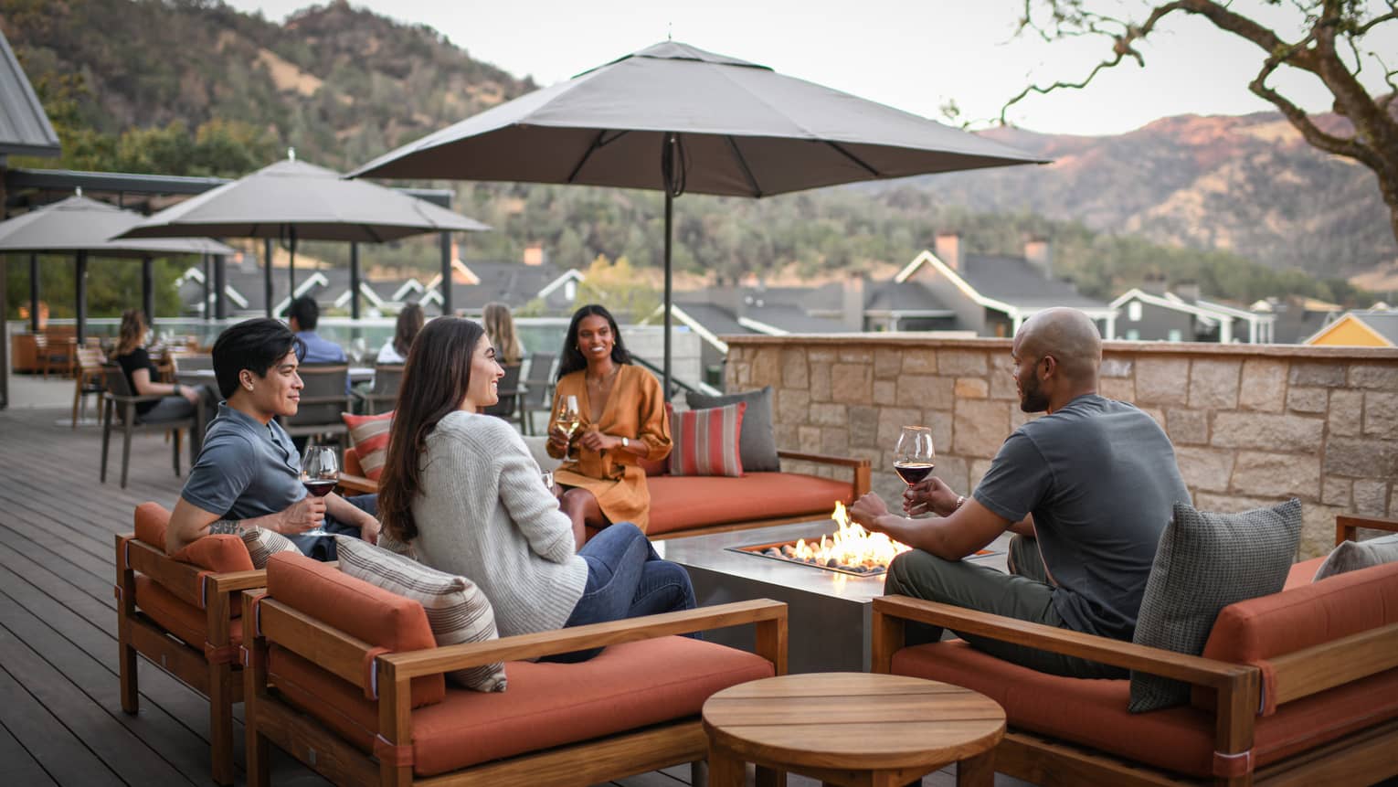 A group of people sitting outside with glasses of wine.
