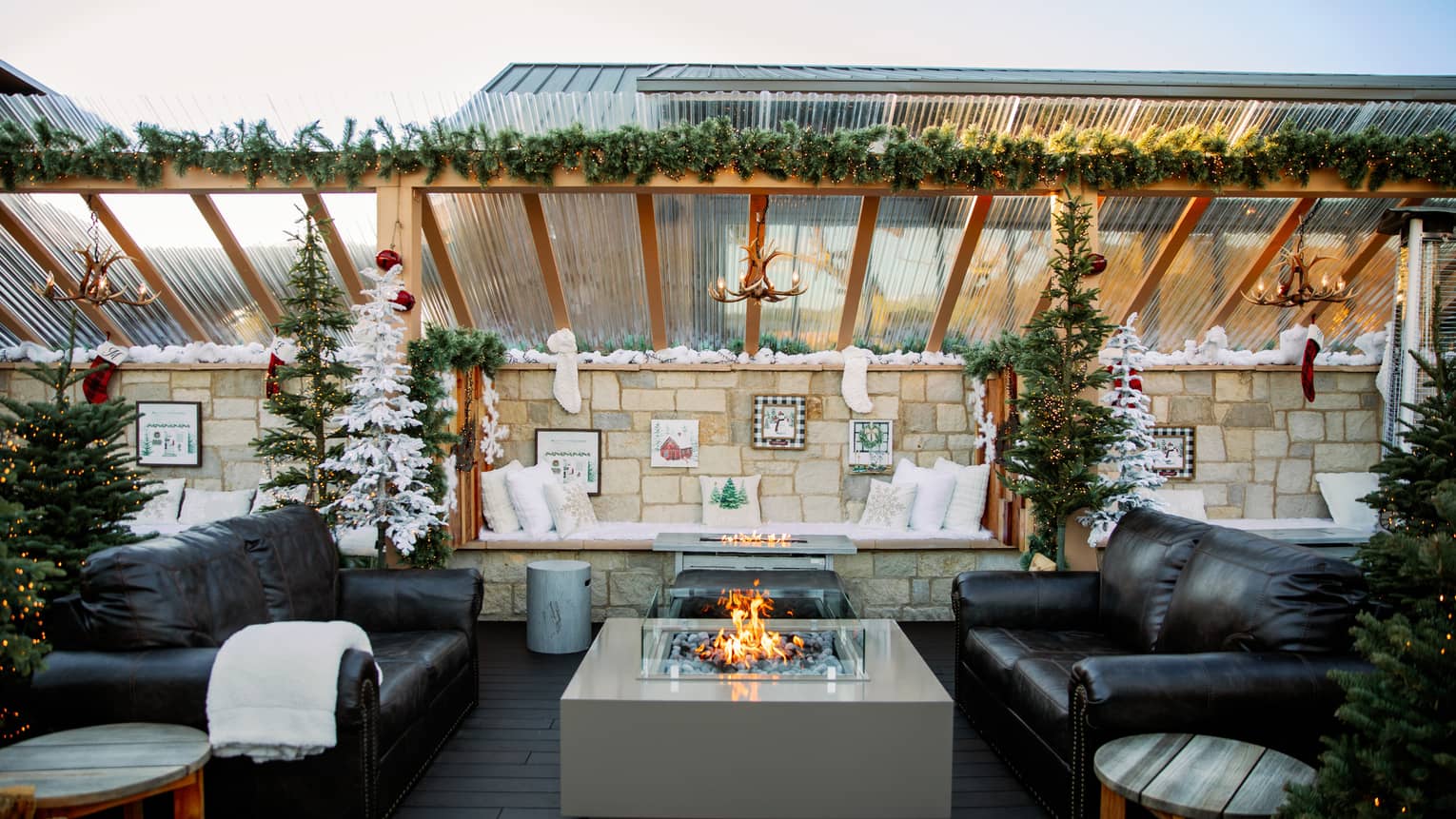Outdoor terrace with two couches and a fire pit, and festive decorations.